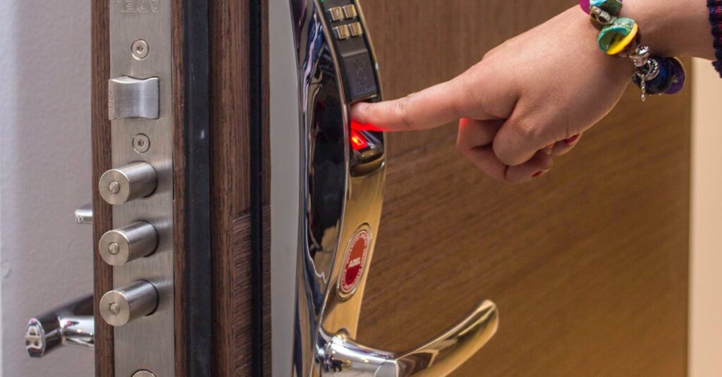 A hand using fingerprint access on a digital security door lock, enhancing safety.